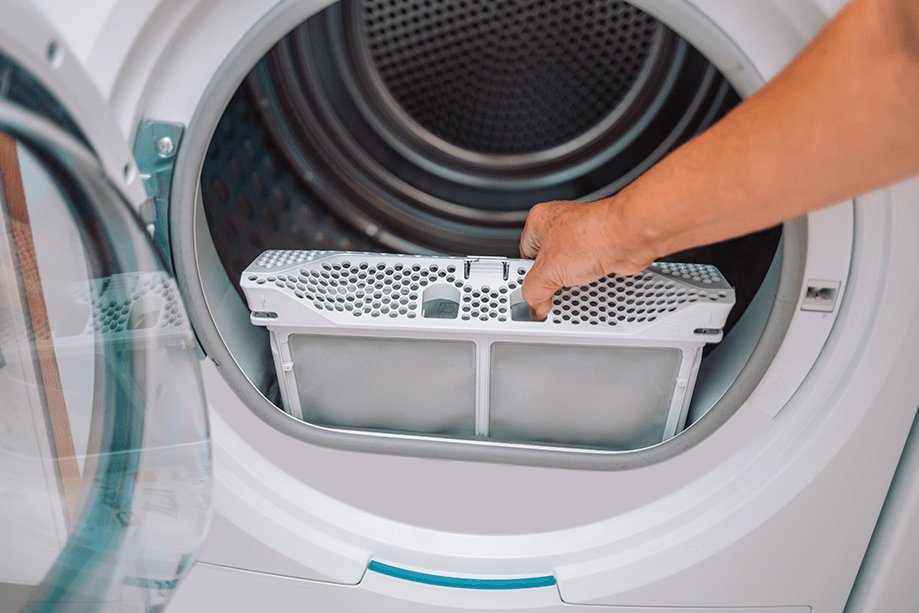 Personne qui nettoie les peluches et la saleté du filtre du sèche-linge. Filtre à charpie pour sèche-linge recouvert de charpie. Retirez les peluches du filtre à air sale de la sécheuse avant d'utiliser la machine.