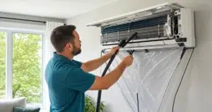 Technicien nettoyant une thermopompe murale dans une maison à Québec l’été